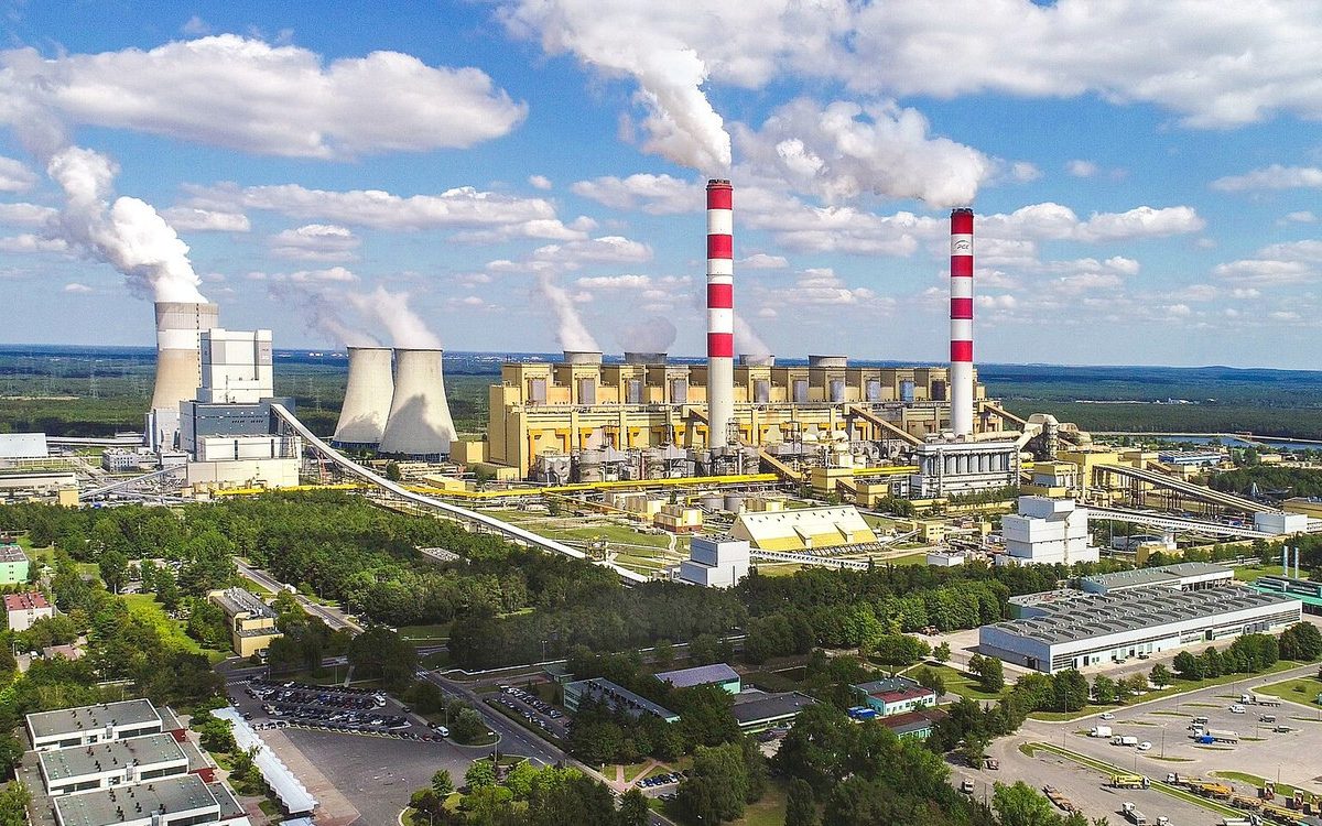 The Belchatow coal power plant in Poland, with two tall striped chimneys and steaming cooling towers
