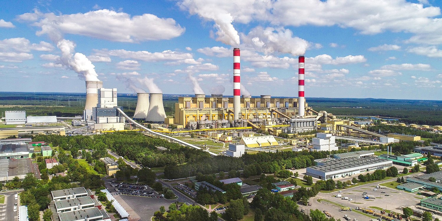 The Belchatow coal power plant in Poland, with two tall striped chimneys and steaming cooling towers