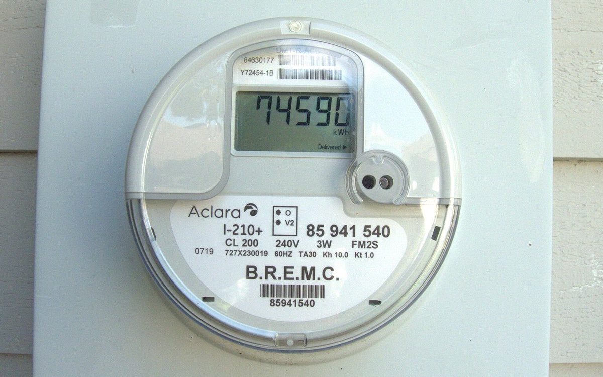 A smart electricity meter on the side of a house showing its kWh reading