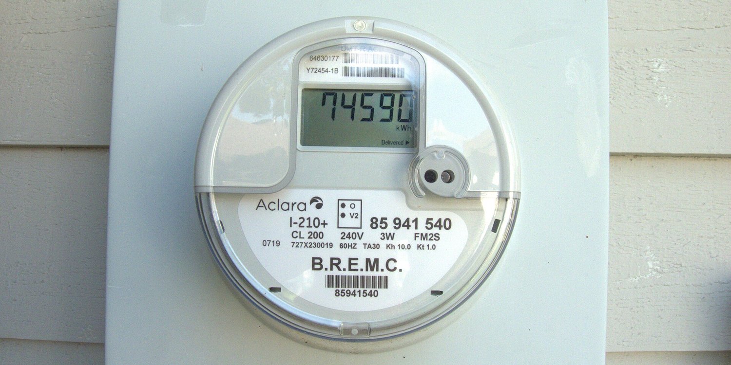 A smart electricity meter on the side of a house showing its kWh reading
